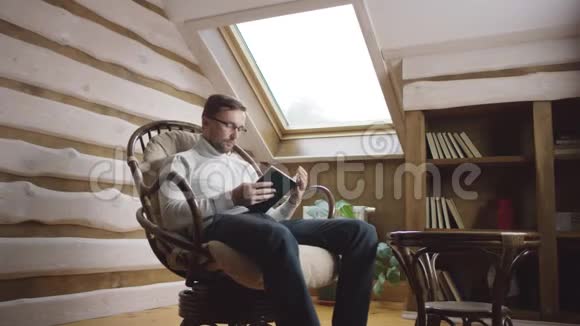 戴眼镜的人在椅子上看书视频的预览图