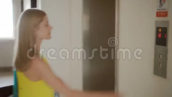 美丽的年轻女子穿着黄色的连衣裙等待电梯按下一个按钮叫电梯视频的预览图