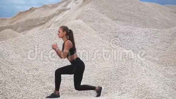 年轻的运动员在她蹲的大自然中做臀部的肌肉锻炼视频的预览图