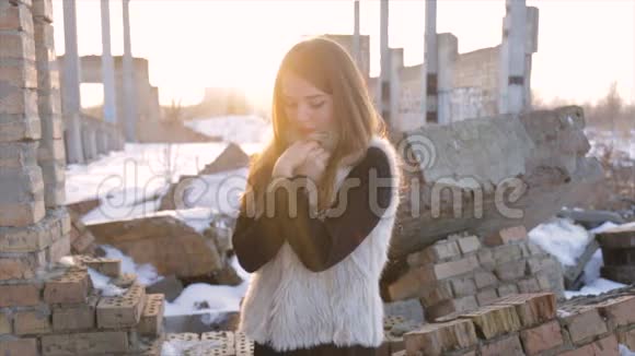一个穿着羊皮外套的女孩在一座废弃的建筑物的背景上视频的预览图