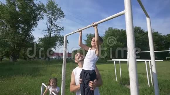 爸爸带着儿子在操场训练幸福的家庭在外面微笑生活方式人们的观念视频的预览图