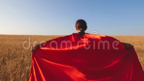 超级英雄女孩带着小麦跑过田野对抗蓝天慢动作视频的预览图
