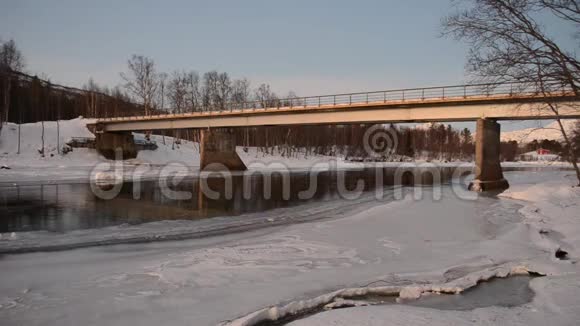 冰封的河水在冬天的金属车桥下岸边白雪皑皑视频的预览图