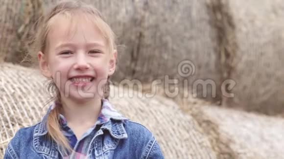 快乐的小女孩看着相机在干草堆的背景下微笑视频的预览图