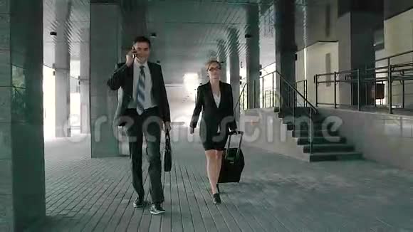 商人在电话里说话商人和女人一起走着拉着她的手提箱视频的预览图