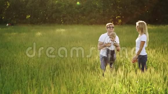 一家人带着年幼的小儿子在田野散步视频的预览图