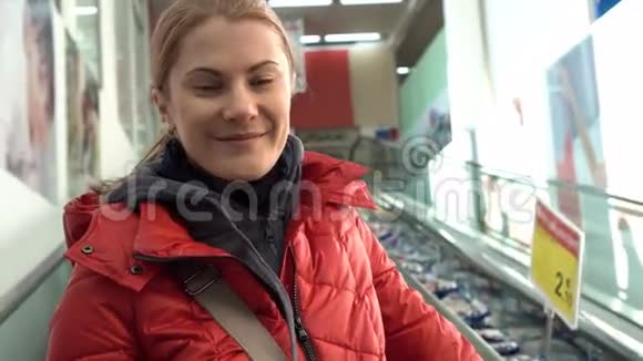 美丽迷人的年轻女子穿着红冬衣在商场里扶梯向上移动购物销售视频的预览图
