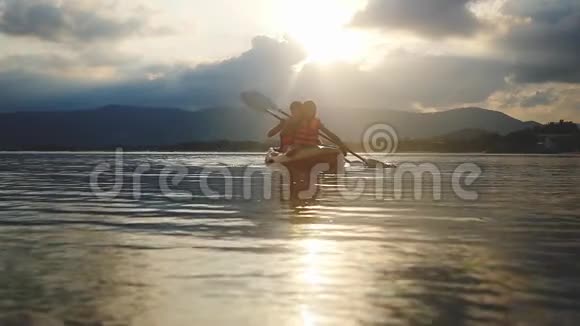 在美丽的夏日夕阳下幸福的微笑夫妇沿着大海划艇游客划船团队合作团结视频的预览图
