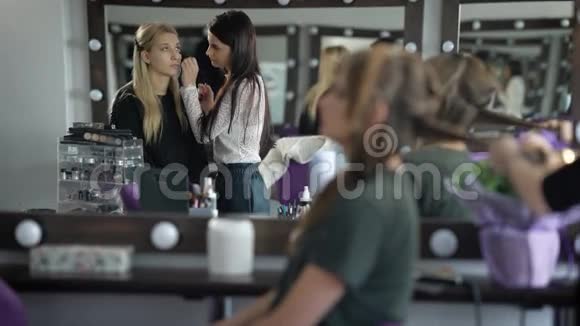 美容店的两个女朋友女孩们准备派对化妆师给这位金发女郎化妆视频的预览图