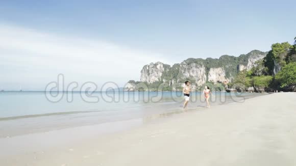情侣在海滩边奔跑快乐的情侣在海上度假时微笑游客视频的预览图