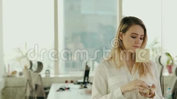 年轻的女商人在办公室的玻璃上粘粘的纸条视频的预览图