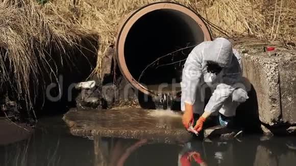 穿着生物危险服和防毒面具的人检查外面的水污染视频的预览图