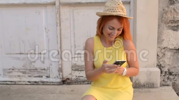红发女游客在古城街道上使用智能手机视频的预览图