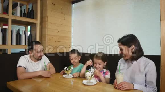 快乐的小女孩和男孩在咖啡馆吃冰淇淋爸爸在那里拍照视频的预览图