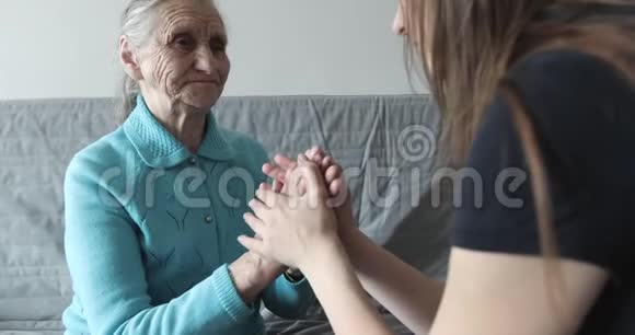 一个年轻的女人握着一个老祖母的皱纹的手视频的预览图