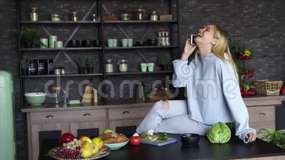 漂亮的女孩在家厨房里用手机说话视频的预览图