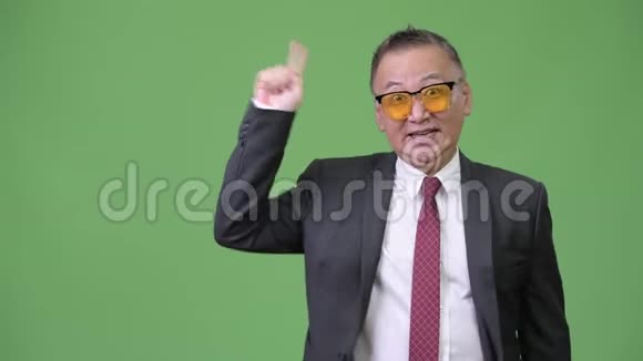 成熟的日本商人戴着绿色背景的太阳镜视频的预览图