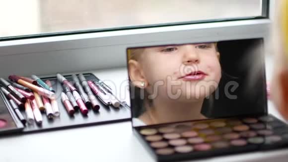 镜子前一个漂亮的小女孩使自己成为一个化妆师视频的预览图