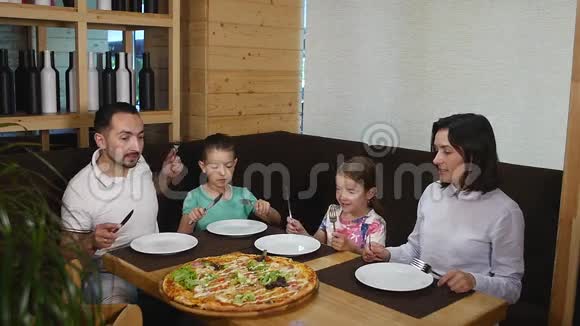 四口之家在咖啡馆享用披萨午餐视频的预览图