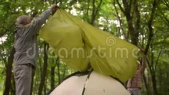 年长的活跃夫妇在树林里搭帐篷视频的预览图