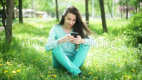 春暖花开的花园里坐在草地上打电话的幸福女人视频的预览图