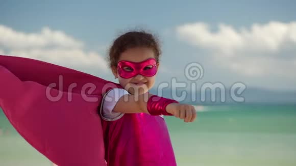 美丽的小女孩在超级英雄服装穿着粉红色斗篷和面具的英雄坐在飞机上视频的预览图