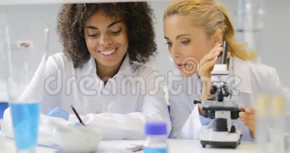 实验室研究人员团队女性专家使用显微镜男性医生讨论测试视频的预览图