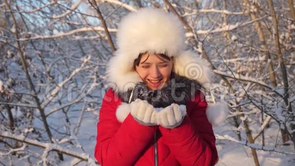 快乐的女孩在日落时吹雪花在冬天的公园里微笑小女孩用手吹雪花视频的预览图