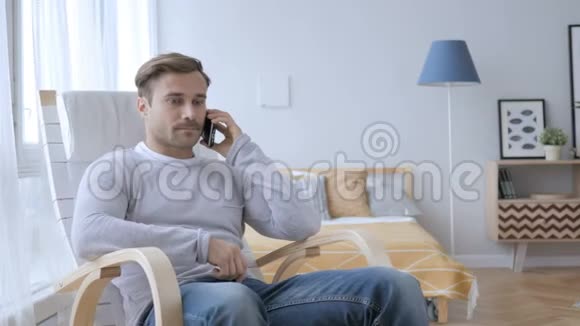 成人在椅子上放松时打电话视频的预览图