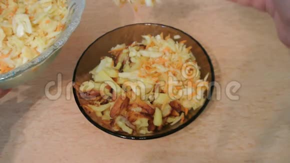 女人用手把凉拌卷心菜和烤土豆放在碗里家庭厨房视频的预览图