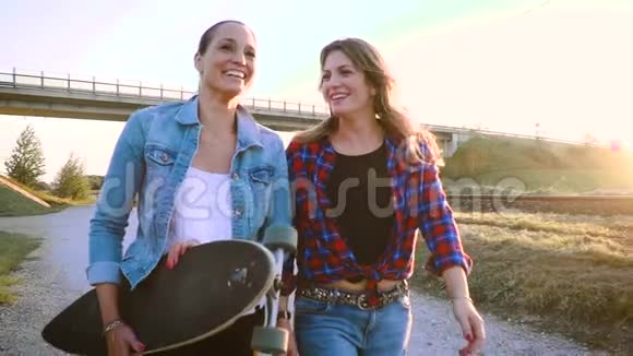 两个年轻漂亮的女人用滑板走路说话视频的预览图