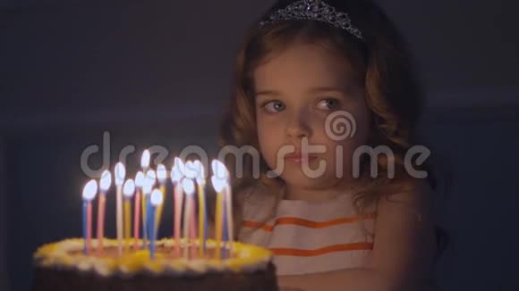 一个小女孩看着生日蛋糕在吹灭蜡烛之前许了个愿视频的预览图