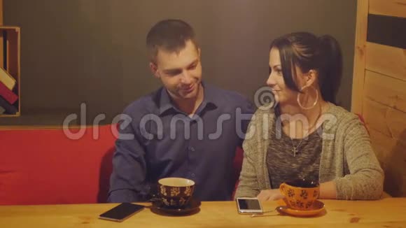 一对夫妇坐在咖啡馆里聊天喝咖啡看电话视频的预览图