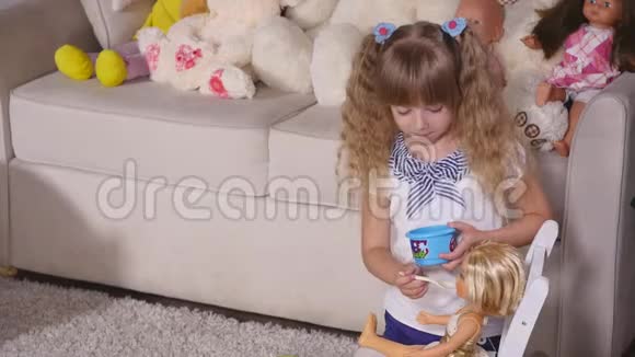 一个女孩用塑料勺子喂娃娃视频的预览图