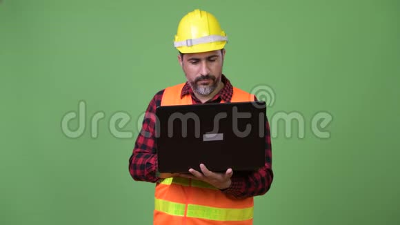 英俊的波斯胡子男建筑工人用笔记本电脑视频的预览图