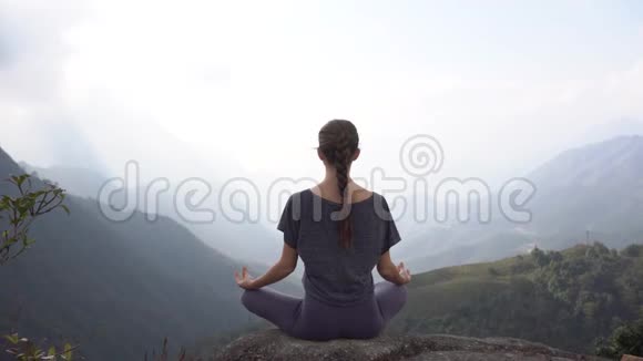 越南萨帕山崖上坐坐冥想姿势的瑜伽女人视频的预览图