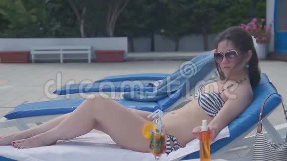 穿比基尼的年轻女性在海滩上晒日光浴涂防晒霜视频的预览图