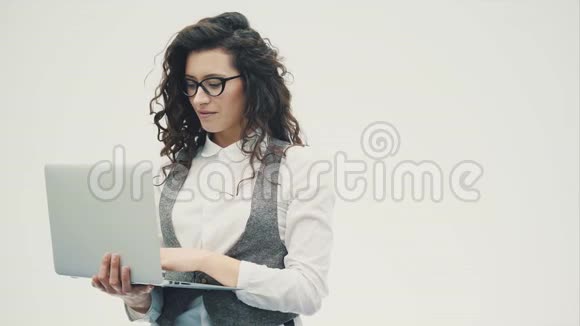戴眼镜的年轻精力充沛的女孩站在白色的背景上视频的预览图