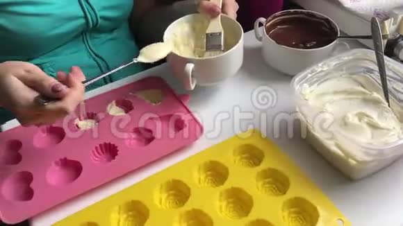 一个女人把融化的白巧克力放进硅胶模具里用于润滑窗体的墙壁做甜点视频的预览图