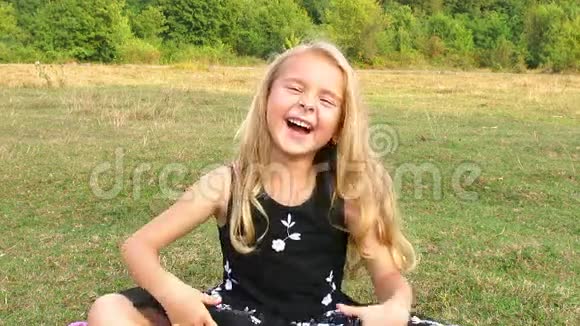 女孩坐在草地上大笑起来视频的预览图