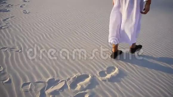 在温暖的夏季傍晚阿拉伯酋长男子穿着国服在沙地山上拍摄特写镜头视频的预览图