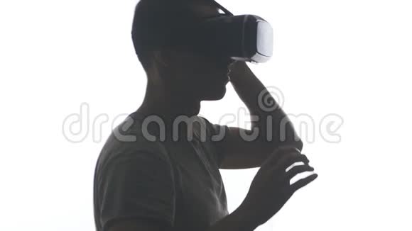 一位戴耳机的年轻人在使用VR耳机方面获得了经验在白色背景下被隔离视频的预览图