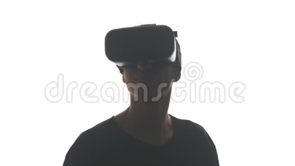 一位戴耳机的年轻人在使用VR耳机方面获得了经验在白色背景下被隔离视频的预览图