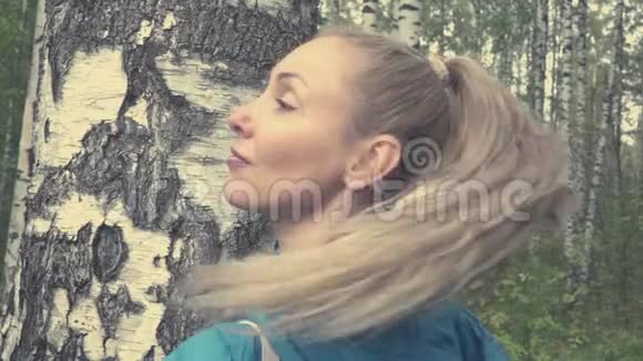 白桦林中一头长发的年轻女子的肖像动作缓慢视频的预览图