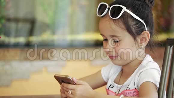 小女孩黑头发坐在咖啡馆里玩智能手机游戏严重的面部退化视频的预览图