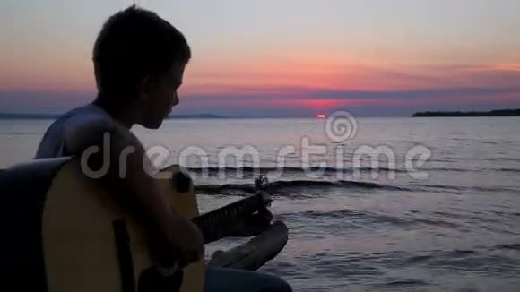 男孩在日落时弹吉他视频的预览图