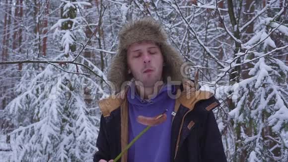 午餐在冬林一个男人在树枝上吃香肠视频的预览图