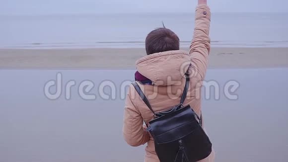女孩站在海边挥舞着她的手视频的预览图