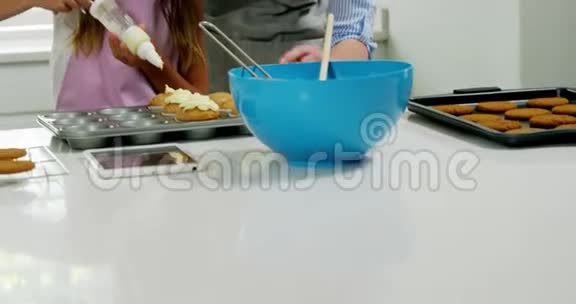 妈妈帮女孩用奶油装饰蛋糕视频的预览图