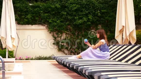 年轻女子坐在沸腾的游泳池旁视频的预览图